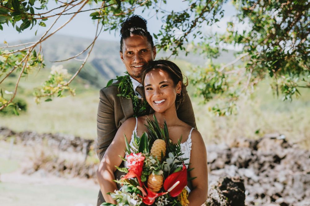 Tropical wedding ceremony setup with bright red flowers and natural greenery.