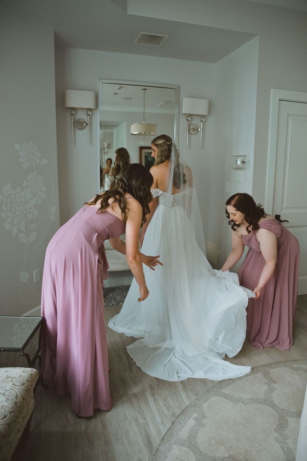 A series of five photos showing bridesmaids in pink dresses helping adjust a white wedding gown.