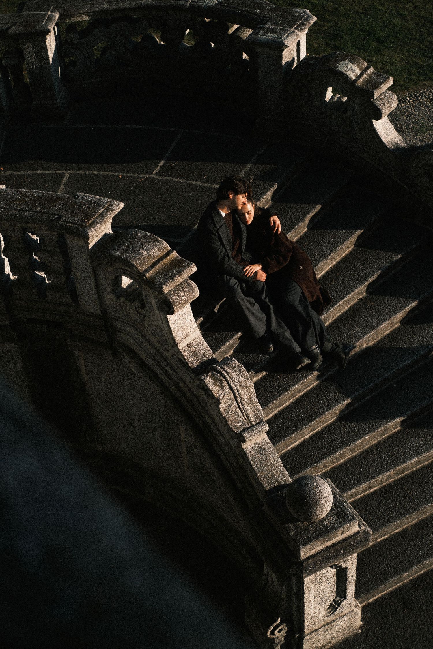 A figure descends a dark concrete staircase casting dramatic shadows in contrasting light and darkness.