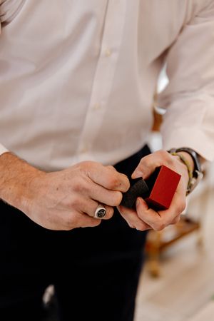 Groom holding a red velvet ring box with wedding bands before the ceremony.