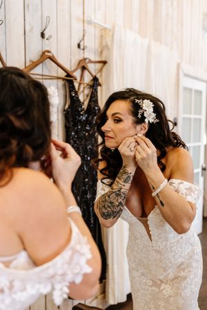 Bride adjusts her earring while looking in a mirror before her winter wedding ceremony.