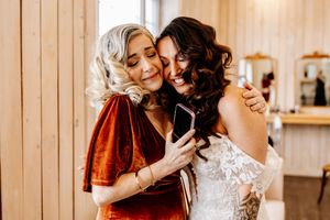 Bride and a friend share a joyful moment looking at a phone together before the wedding.