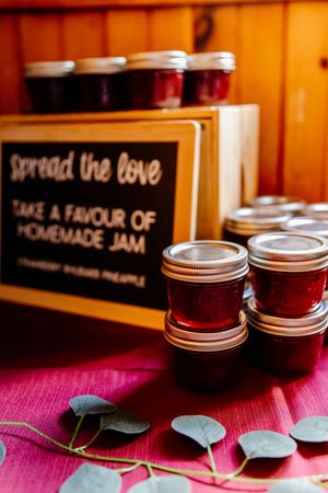 Homemade jam wedding favors displayed with a Spread the Love chalkboard sign on a pink tablecloth.