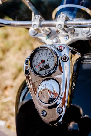 Close-up of vintage motorcycle chrome speedometer and controls with reflection of wedding couple.
