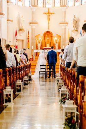 Bride and groom stand at the altar of an ornate Catholic church during ceremony.
