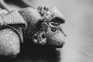 Black and white close-up of sparkly bridal shoes with crystal jewelry and teardrop pendant.