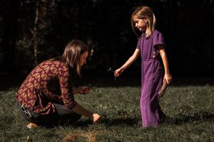 Children playing and searching for items in grass during outdoor activities.