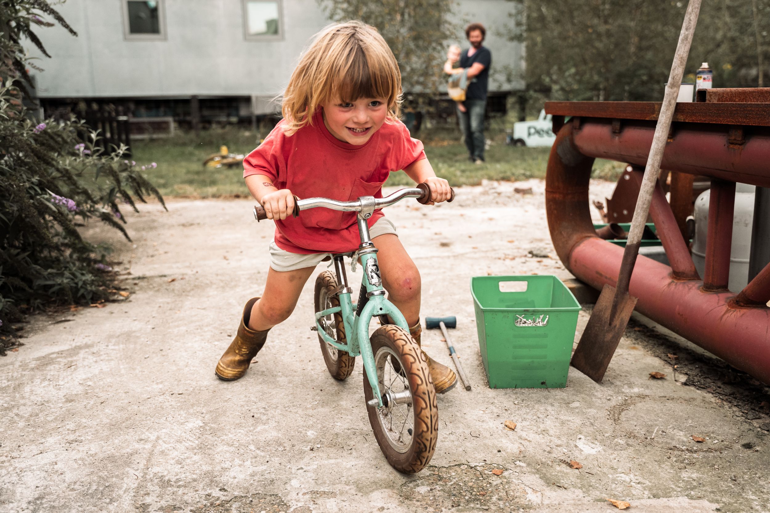 Young child riding a small bicycle on a gravel path outdoors.