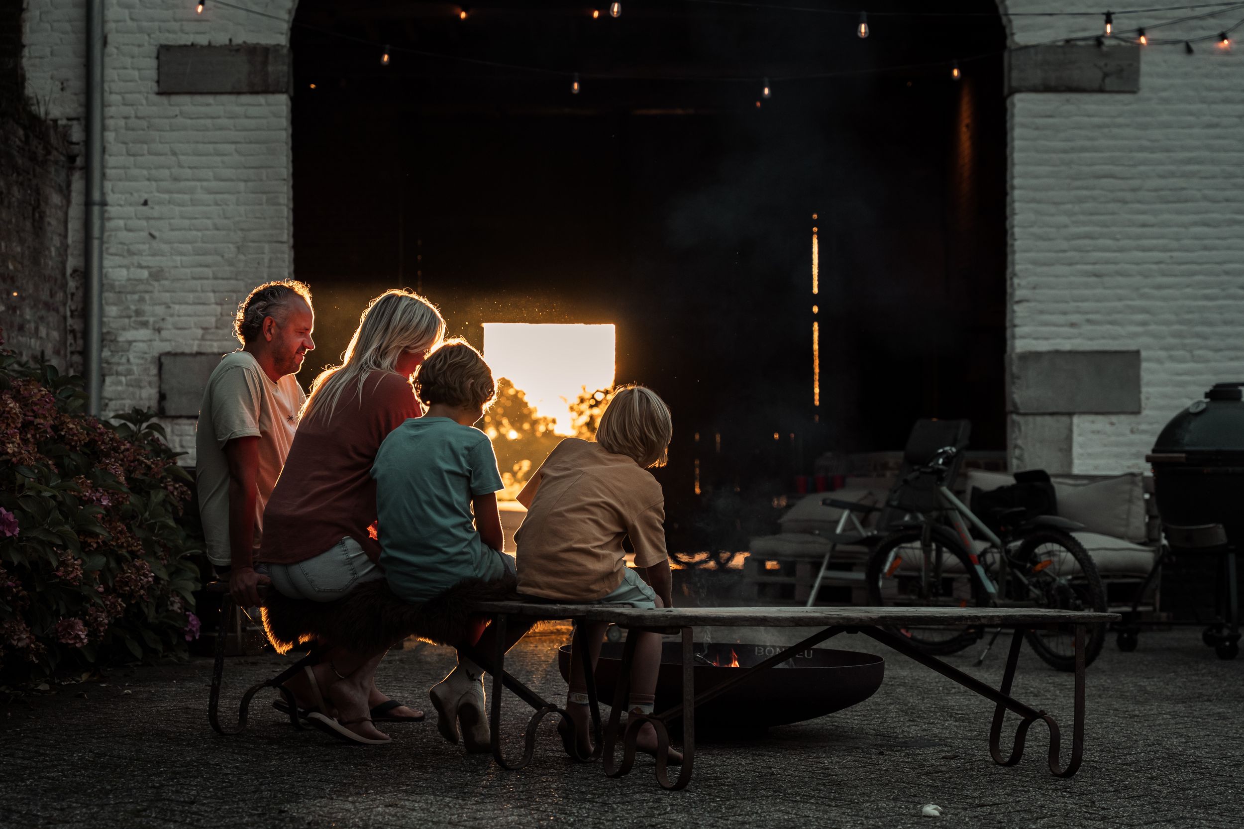 People gathered outside at dusk with warm glowing light in background.