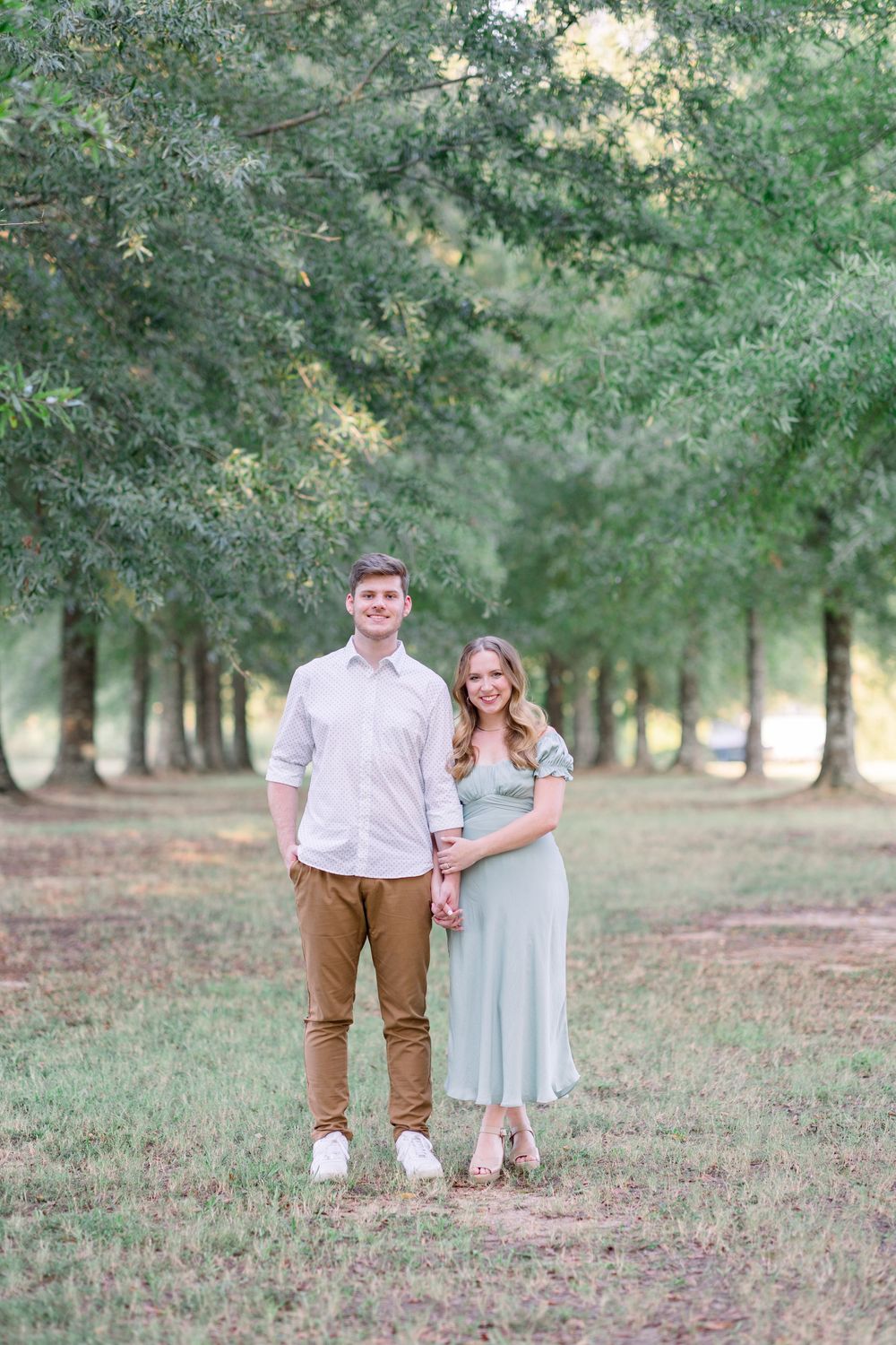 A couple in coordinated outfits sharing a romantic moment together in a wooded outdoor setting.