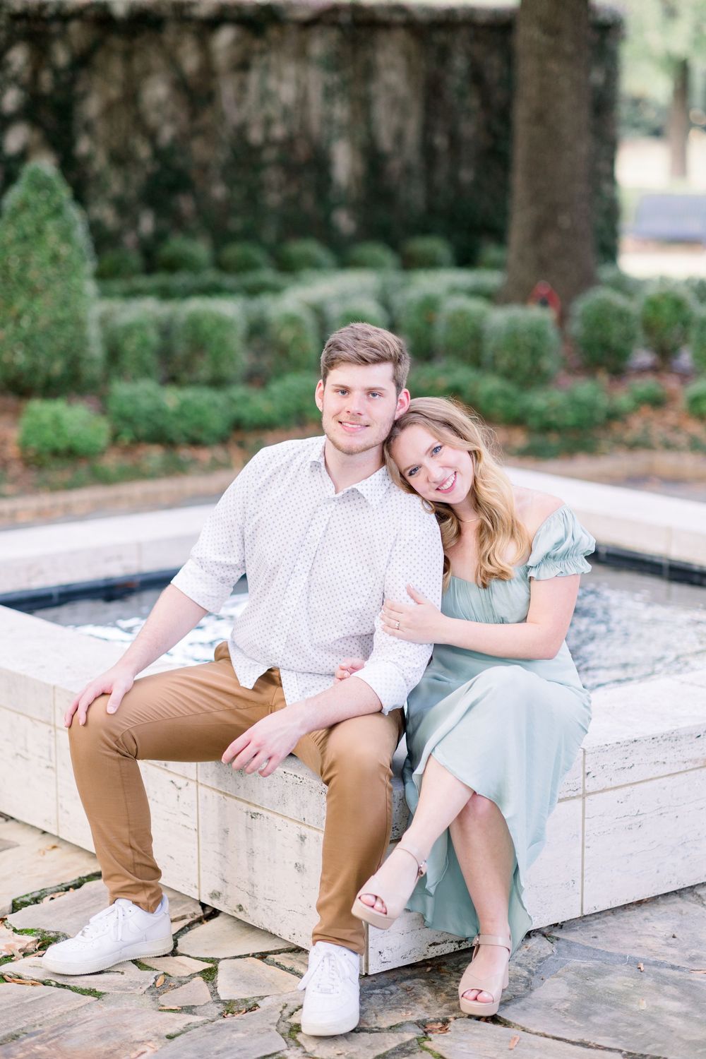 A couple sits together on stone steps in a romantic outdoor photoshoot series showing playful and intimate moments.
