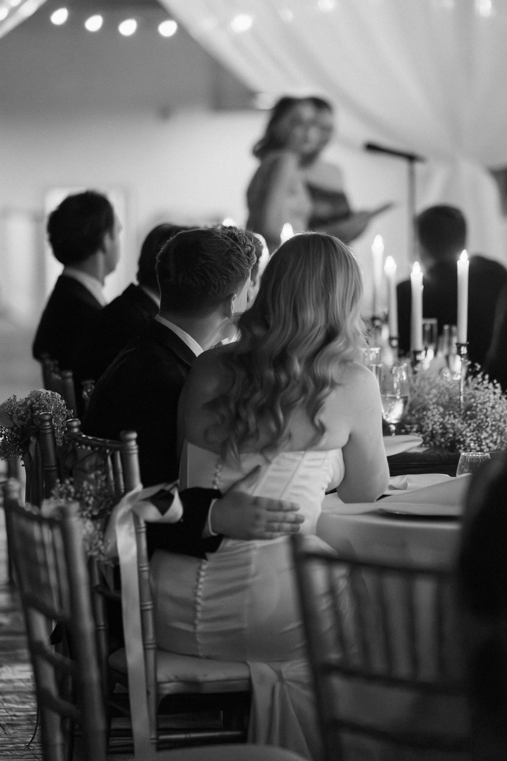 Black and white photo of wedding reception guests seated at tables with candlelit decor and twinkling lights overhead at Georgia wedding