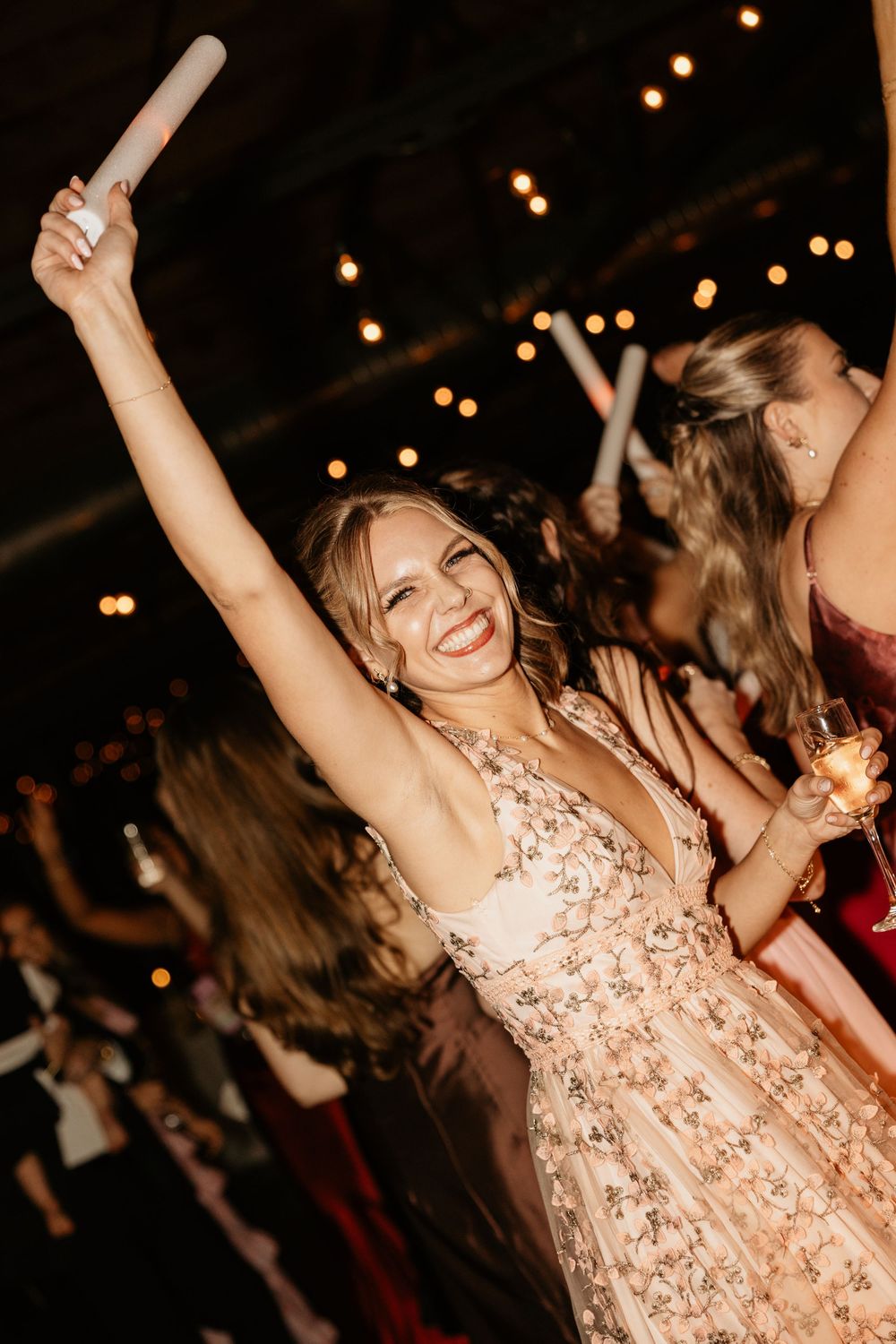 A person in a pink sequined dress dances joyfully at a party with twinkling lights in the background at Summerour Studio in Atlanta, Georgia