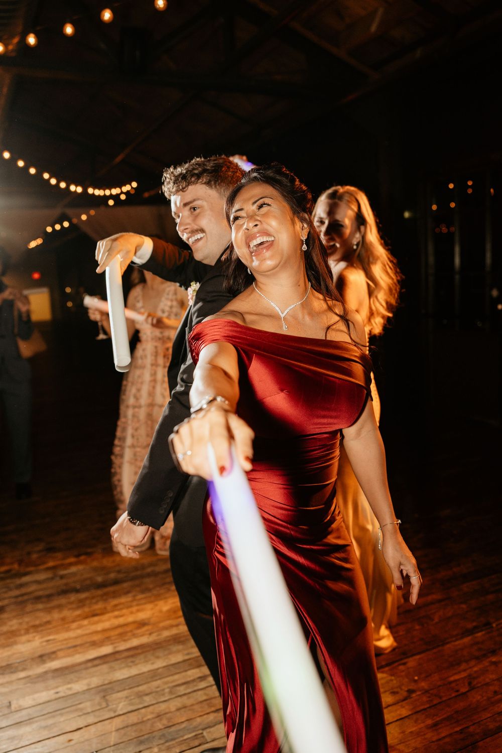 Couple dancing together on a wooden floor under warm lighting in a romantic burgundy velvet dress at Atlanta wedding