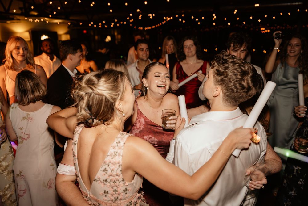 Wedding guests dance and celebrate on a dimly lit dance floor with twinkling lights overhead during a reception party at Georgia wedding