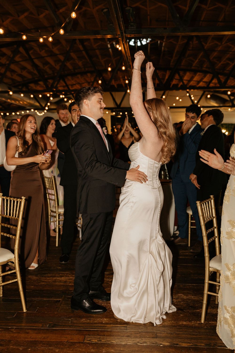 Wedding guests dance together under string lights in a wedding venue located in Atlanta