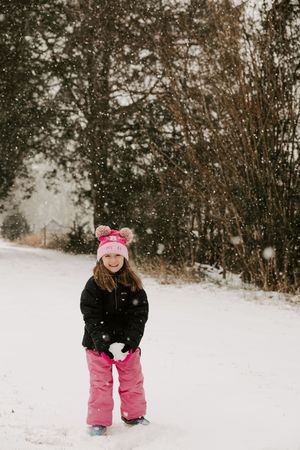 A sequence of winter scenes shows someone in pink snow pants and black jacket playing in fresh fallen snow.