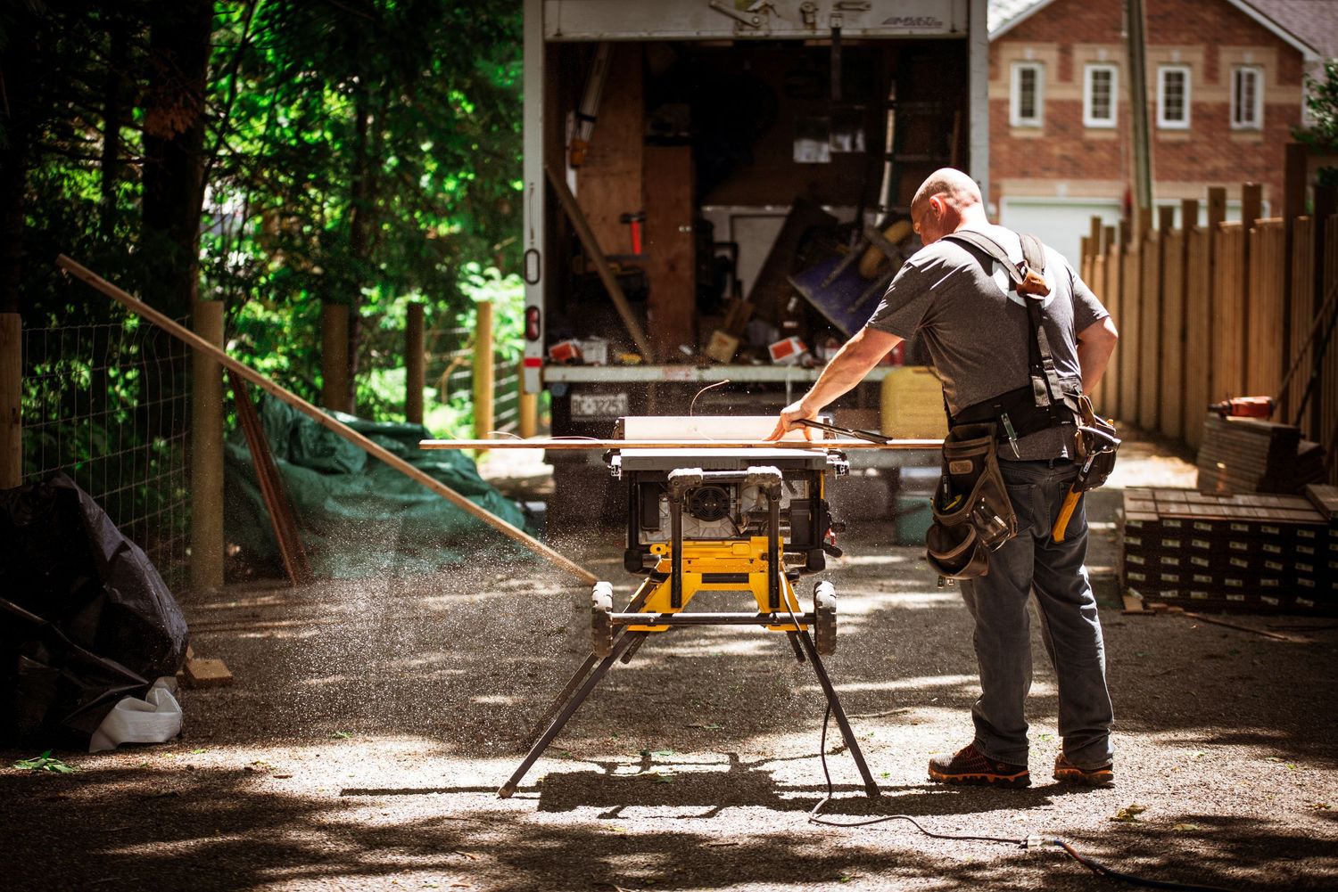 An employee for Align Decking cutting wood on a table saw during a branding photoshoot in Beaverton, Ontario.