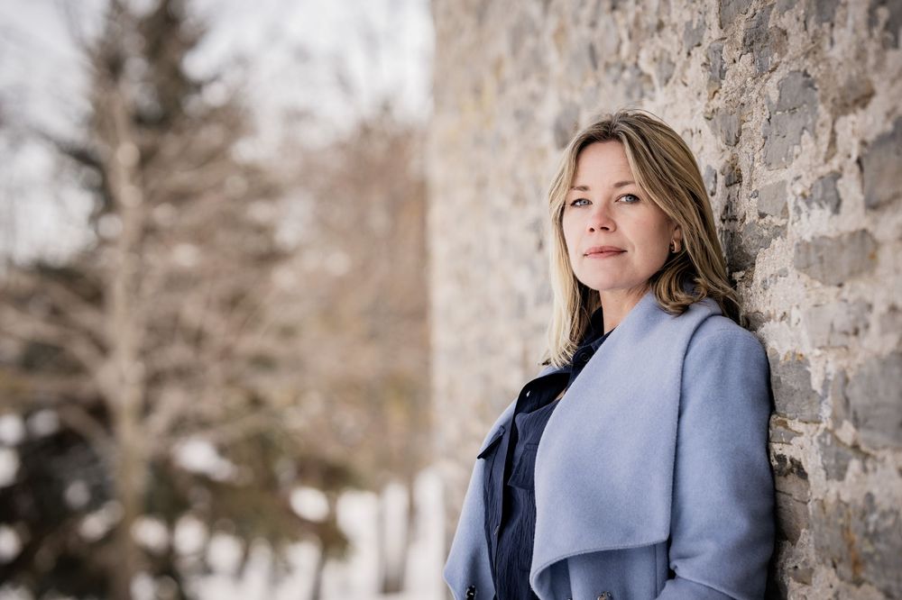 A woman posing against an old heritage building for headshots in Beaverton, Ontario.