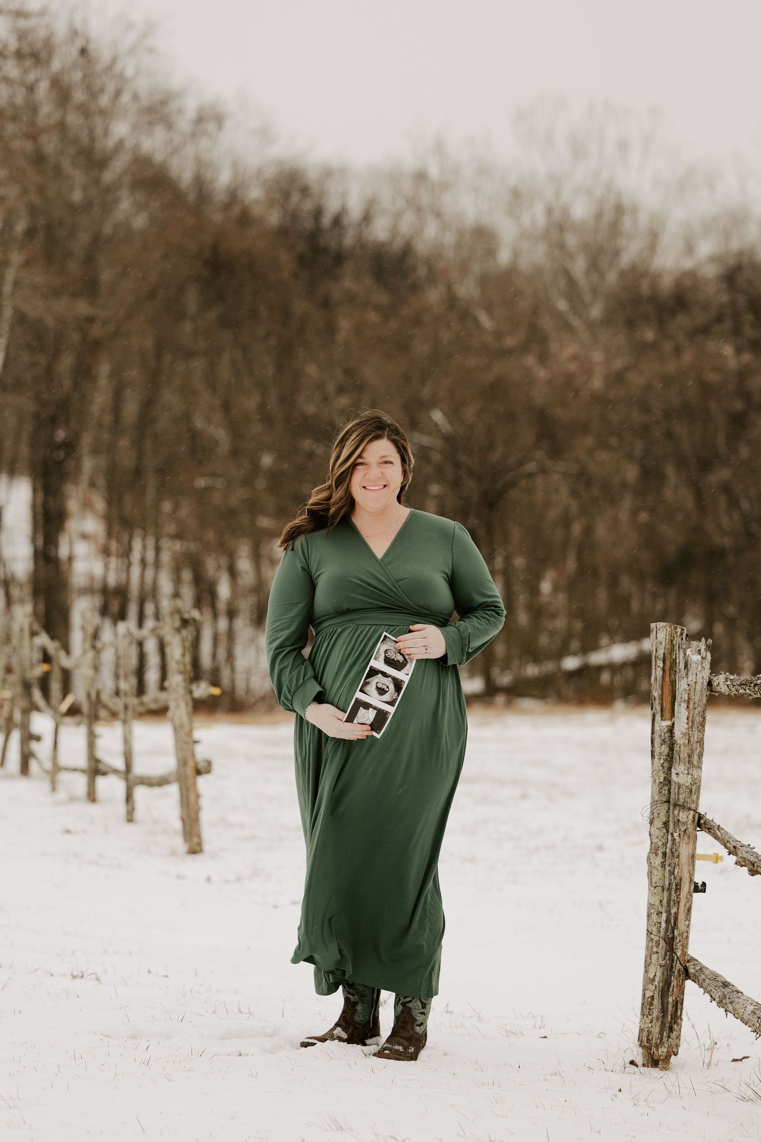 A series of winter maternity photos showing a person in a green dress standing in the snow near a wooden fence.