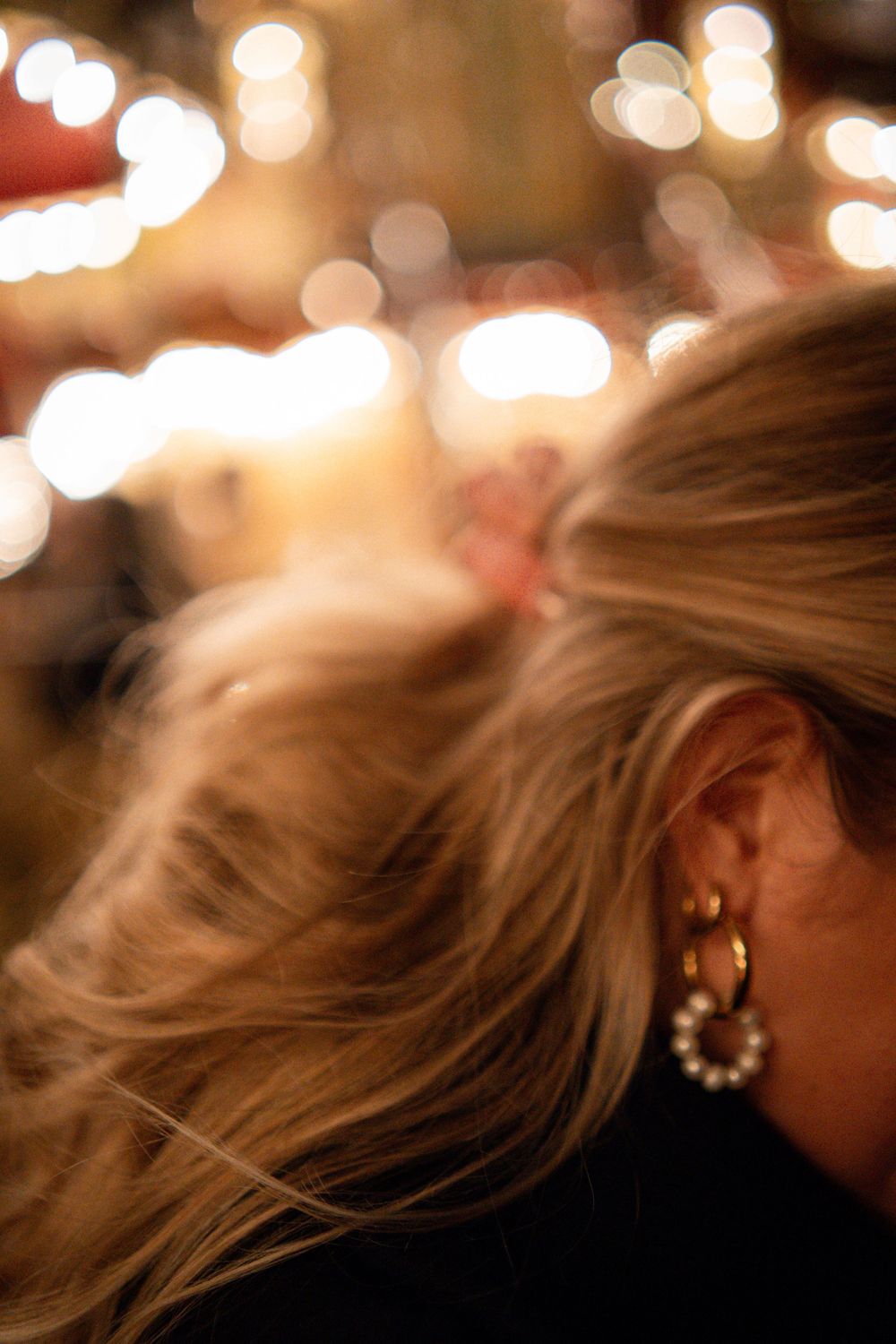 Close-up of blonde hair illuminated by warm bokeh lights in the background.