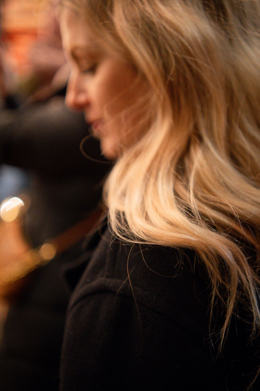 Side profile silhouette of wavy blonde hair against warm lighting.
