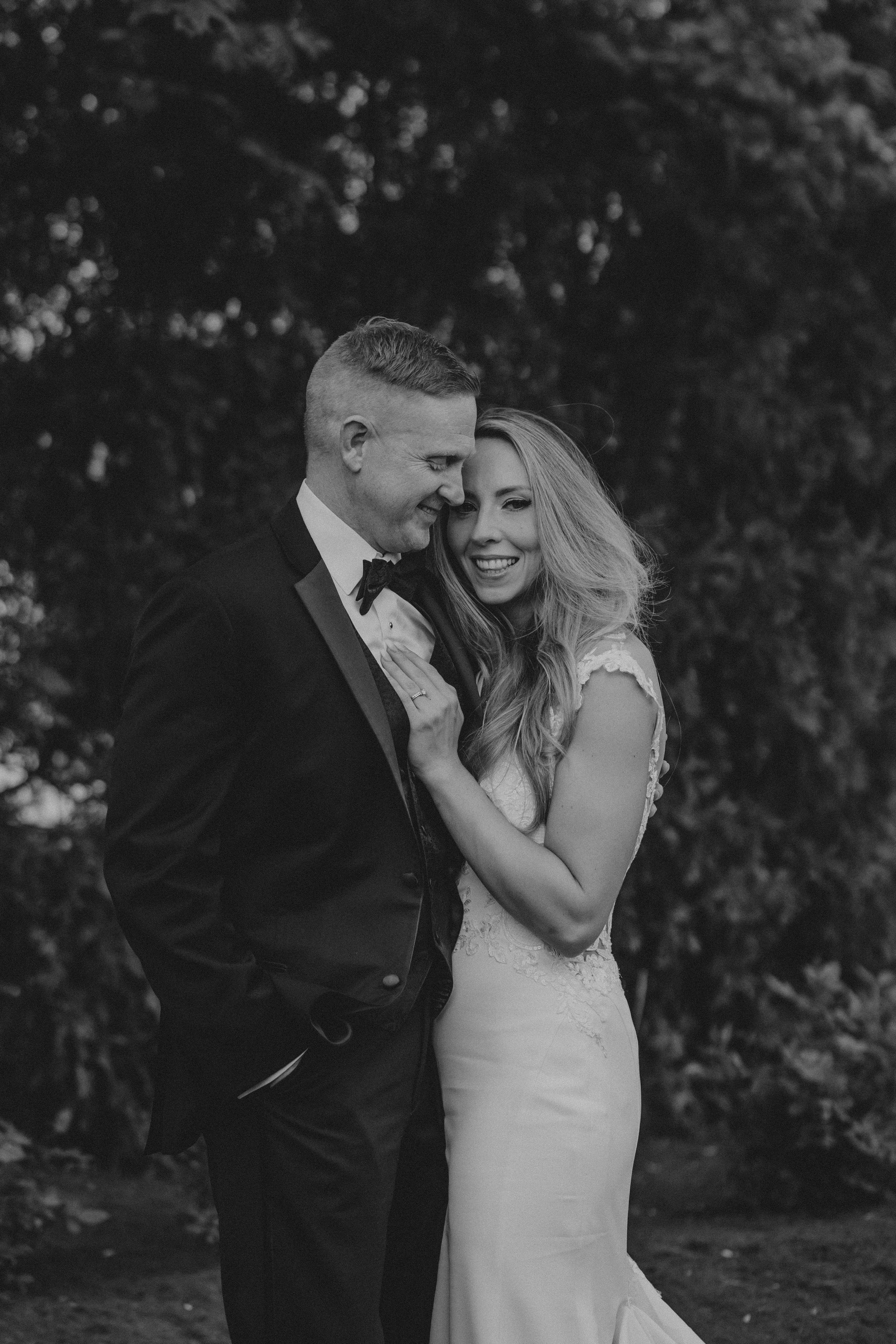 A black and white romantic wedding photo series showing a couple embracing outdoors.