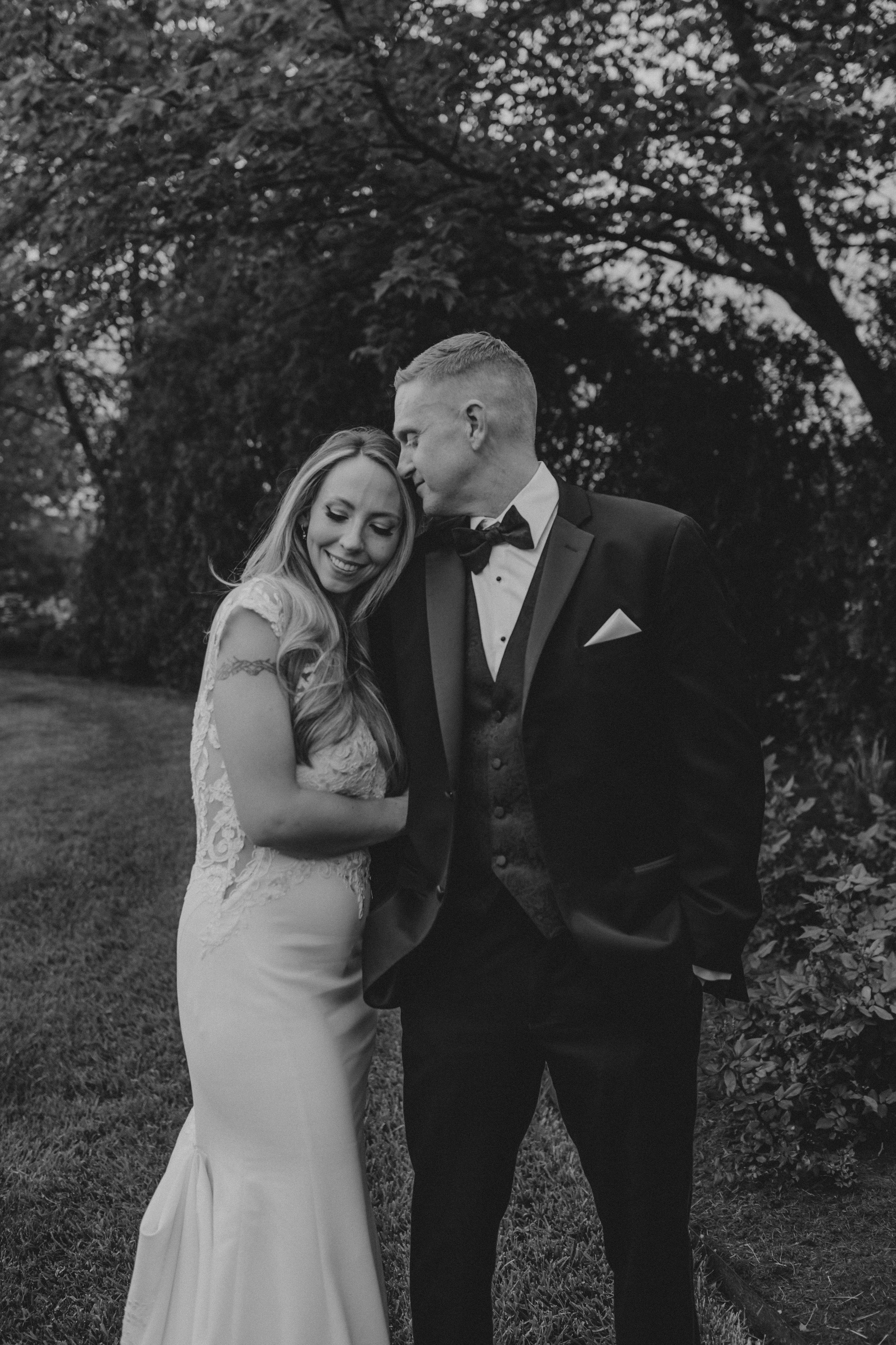 A romantic black and white photo series of a couple sharing intimate moments in a garden setting during their wedding.