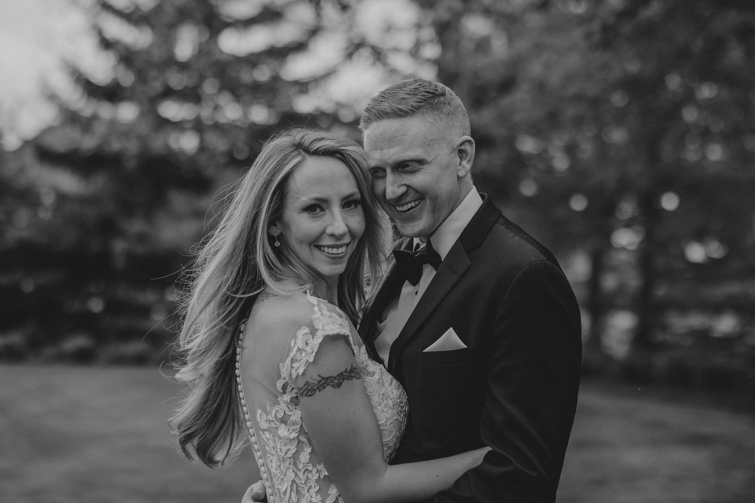 Black and white wedding photos show a couple embracing and laughing together in an outdoor garden setting.