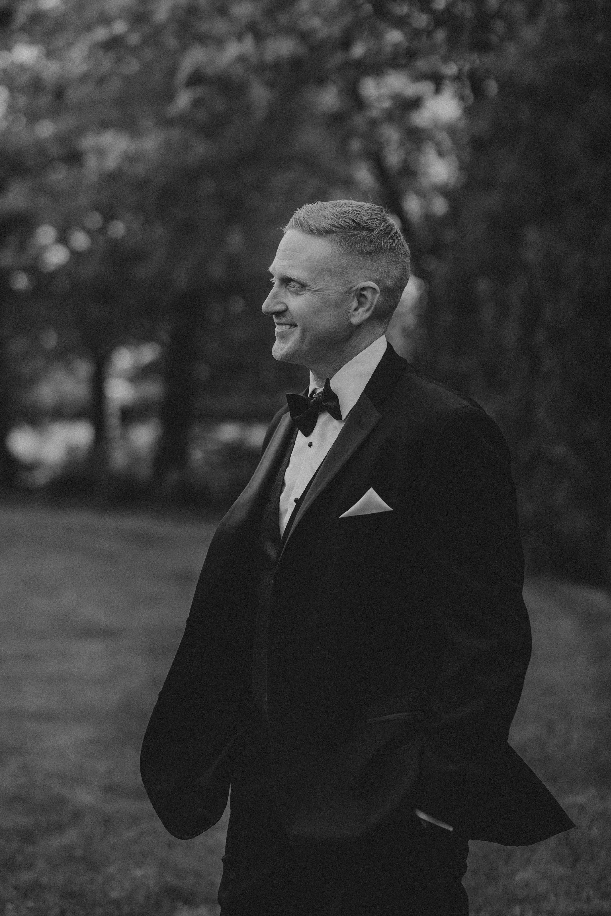 Black and white photo series showing a person in a suit standing outdoors and smoking a cigarette.