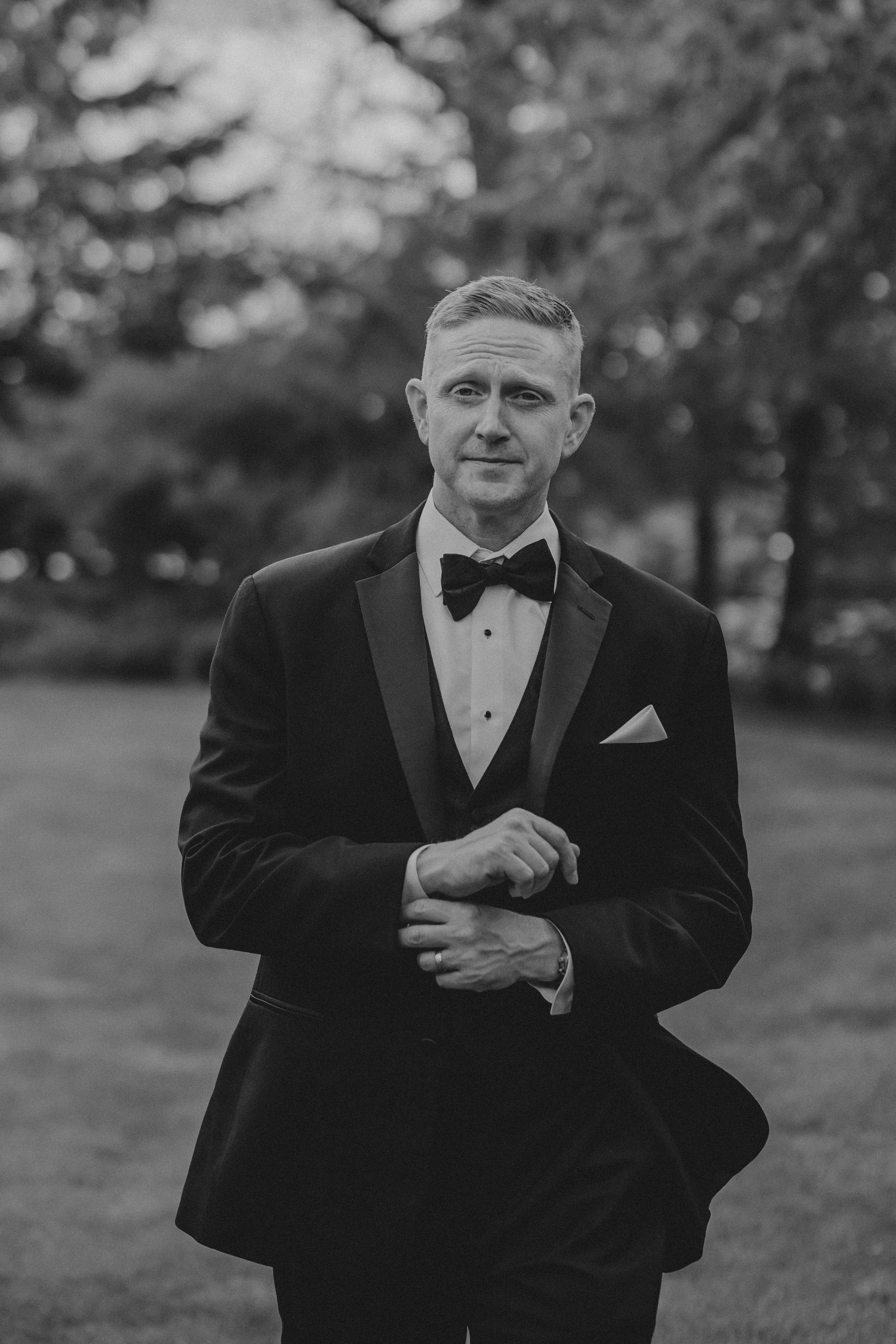 Black and white photo series showing a person in a tuxedo making playful gestures and expressions outdoors.
