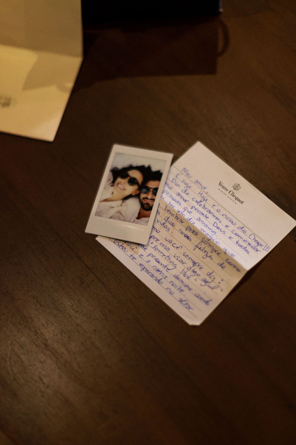 Handwritten notes and small photos arranged on a dark wooden surface in a sequential pattern.