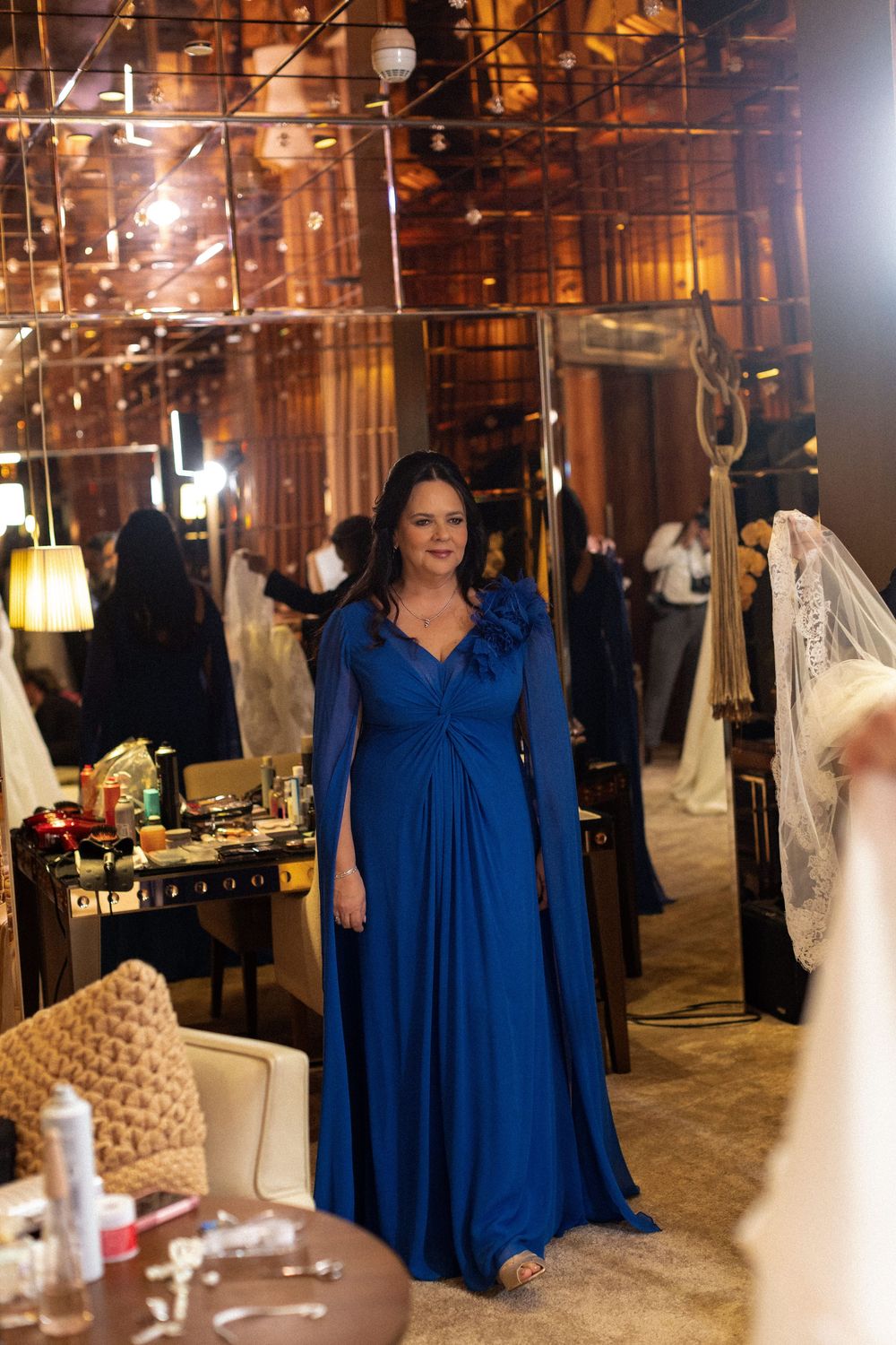 Wedding dress shop interior with royal blue decor and mannequins displayed in warm ambient lighting.