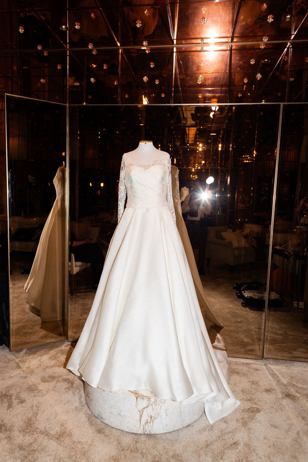 White wedding dress displayed on mannequin in dimly lit room with twinkling lights.