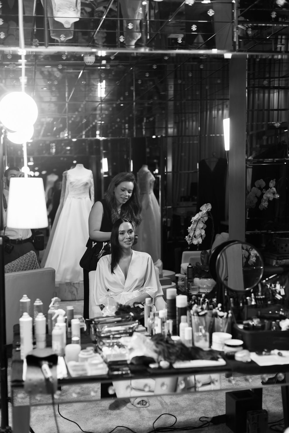 Black and white photo series showing a dressing room vanity with mirrors, lights, and cosmetics arranged on the counter.