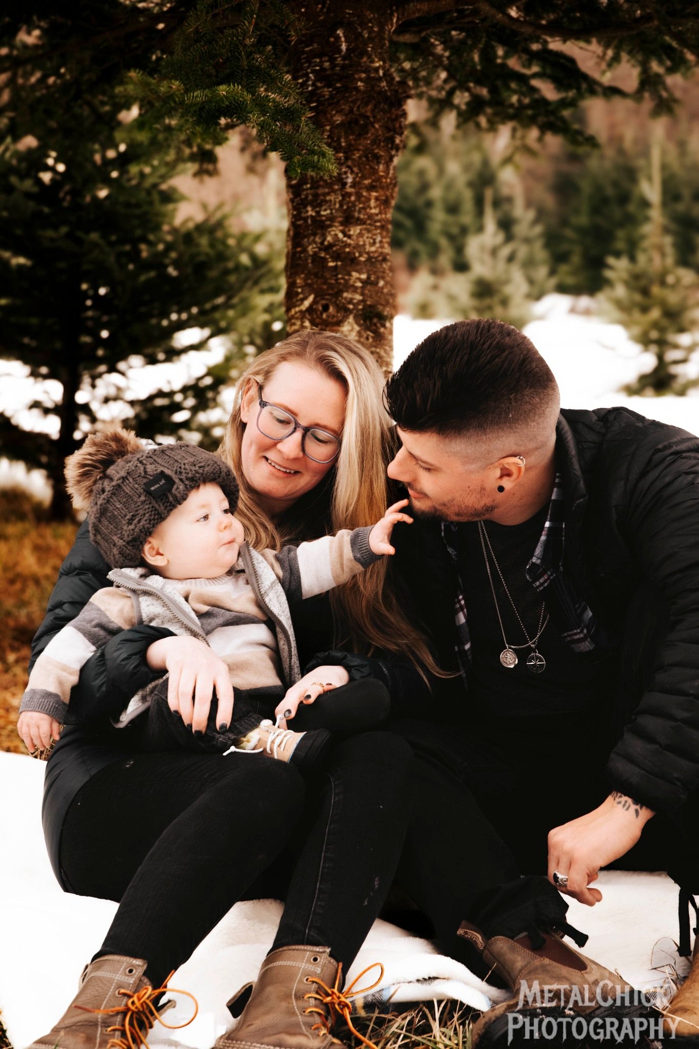 Small Family portrait by Northern Exposure featuring a baby and parents in a tree farm.