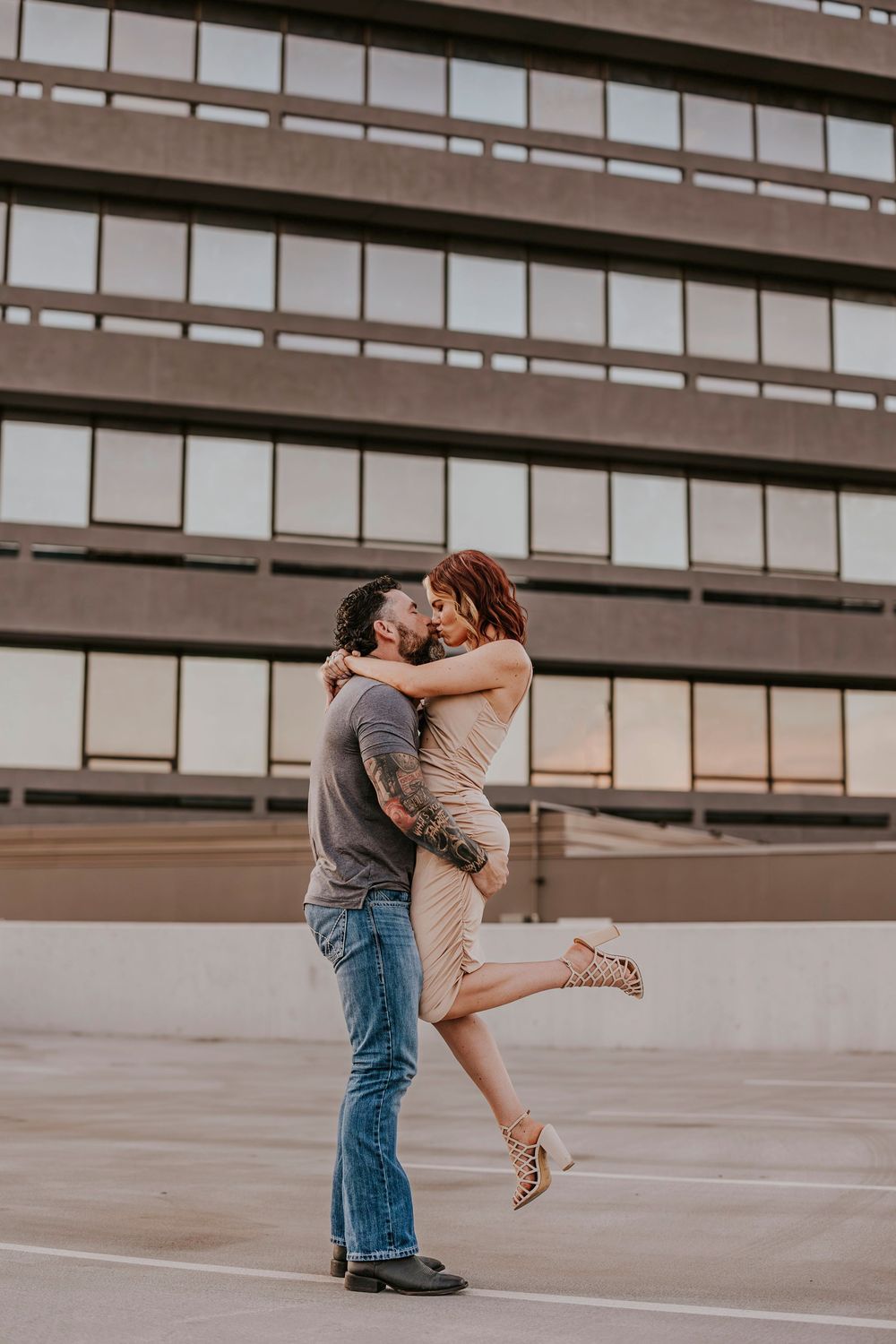 A couple dancing and embracing on a rooftop parking structure at sunset.