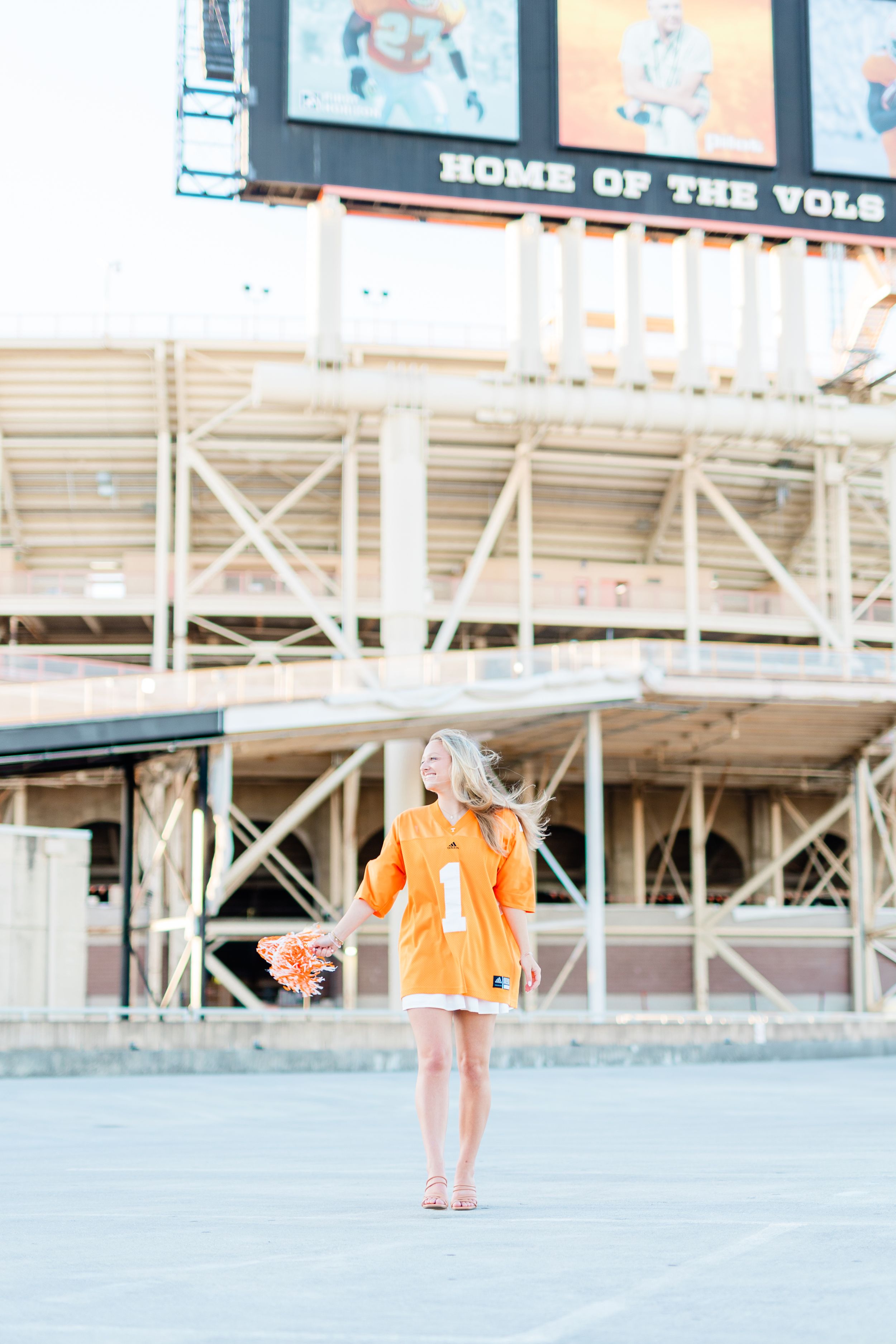 A person in an orange dress stands outside Neyland Stadium's Home of the Vols entrance in Knoxville, Tennessee.