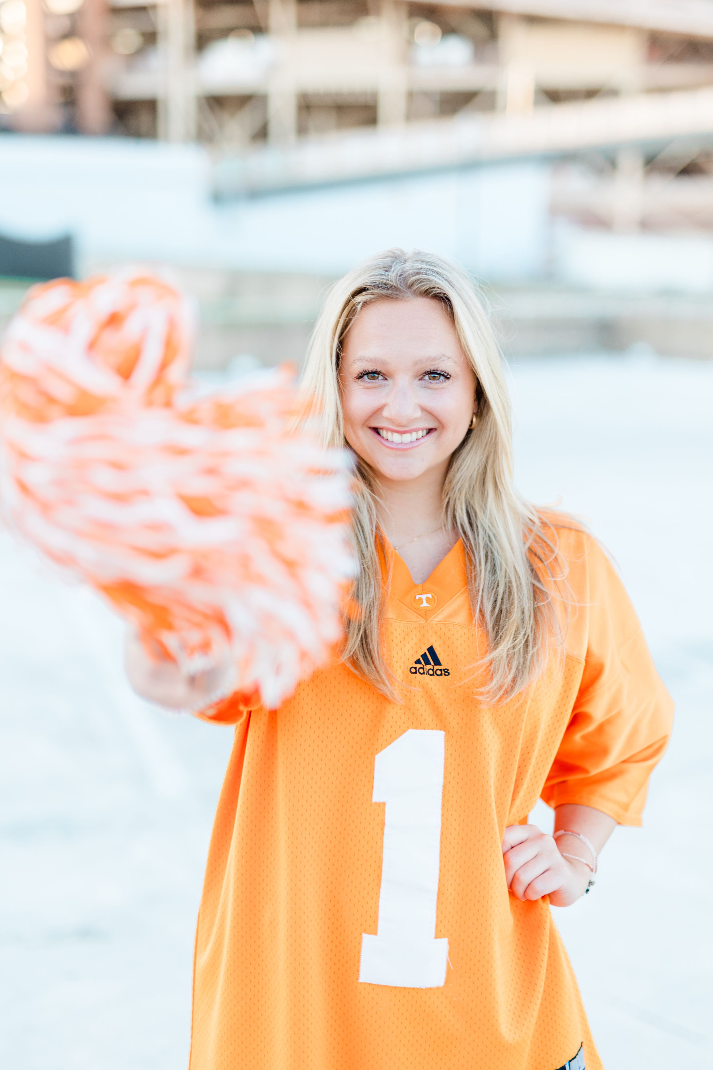 Someone wearing a bright orange sports jersey with a white number stands in front of a light background.