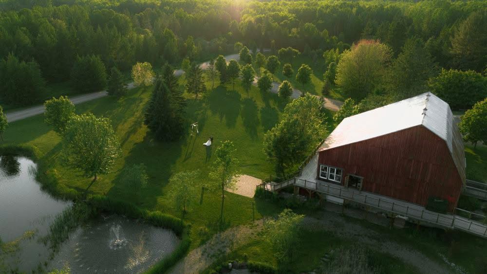 Aerial drone view of a lush green neighborhood with houses and trees along a winding river during sunset.