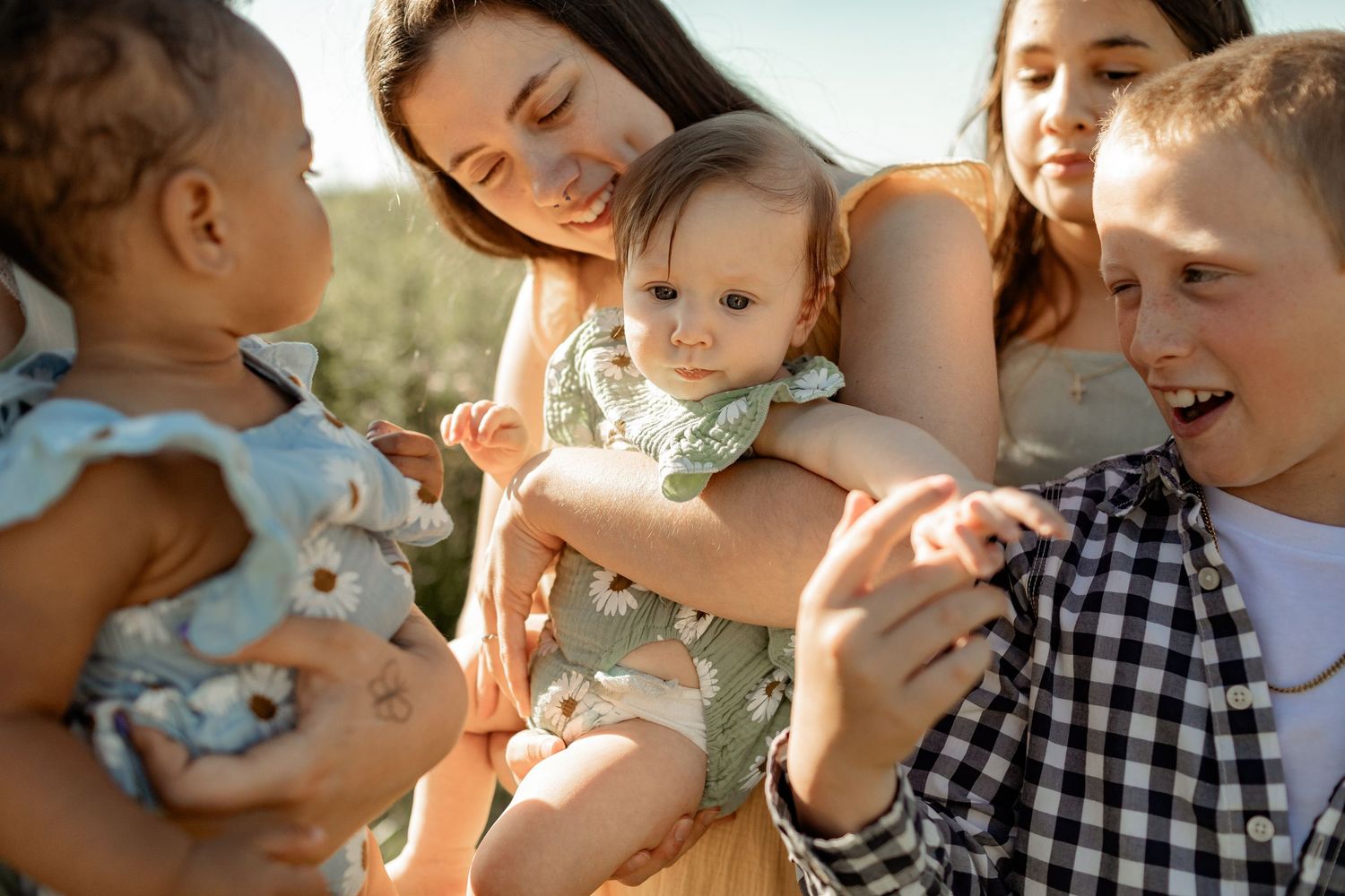 A joyful outdoor gathering of people sharing smiles and laughter in warm sunlight.