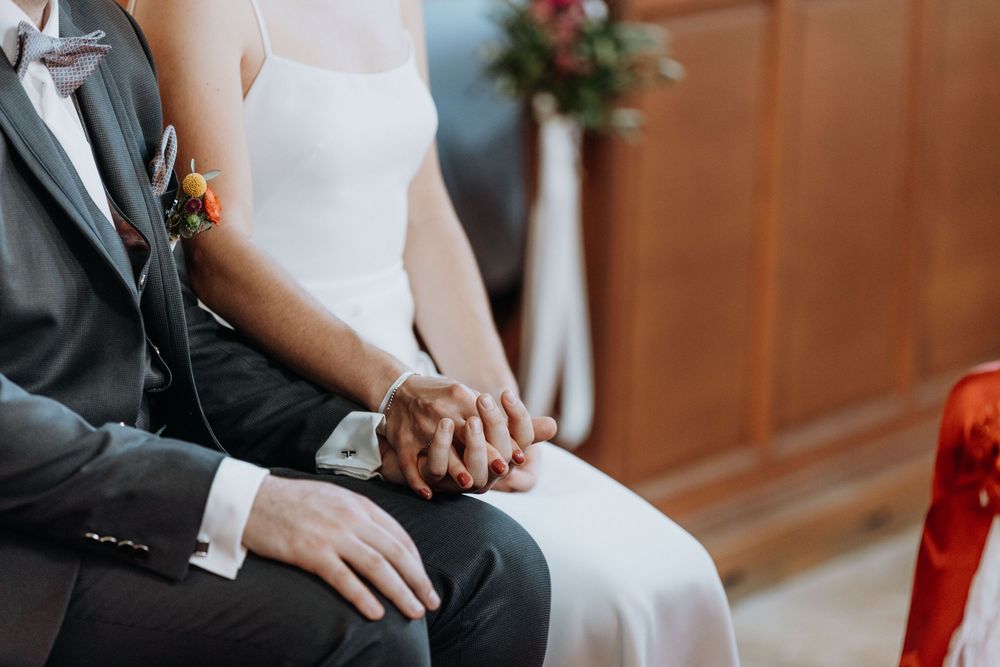 Close-up of formal wedding attire and decorative elements in church setting.