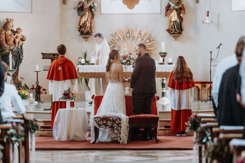 Interior view of a church sanctuary decorated with religious statues and wedding decor.