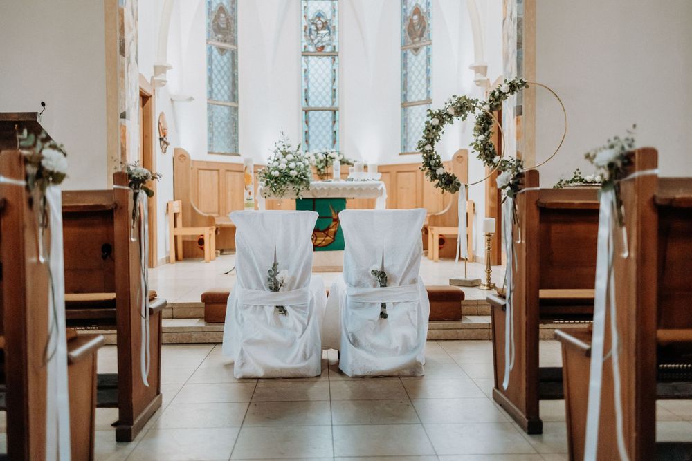 Long center aisle of church sanctuary with white decorated chairs and altar in distance.