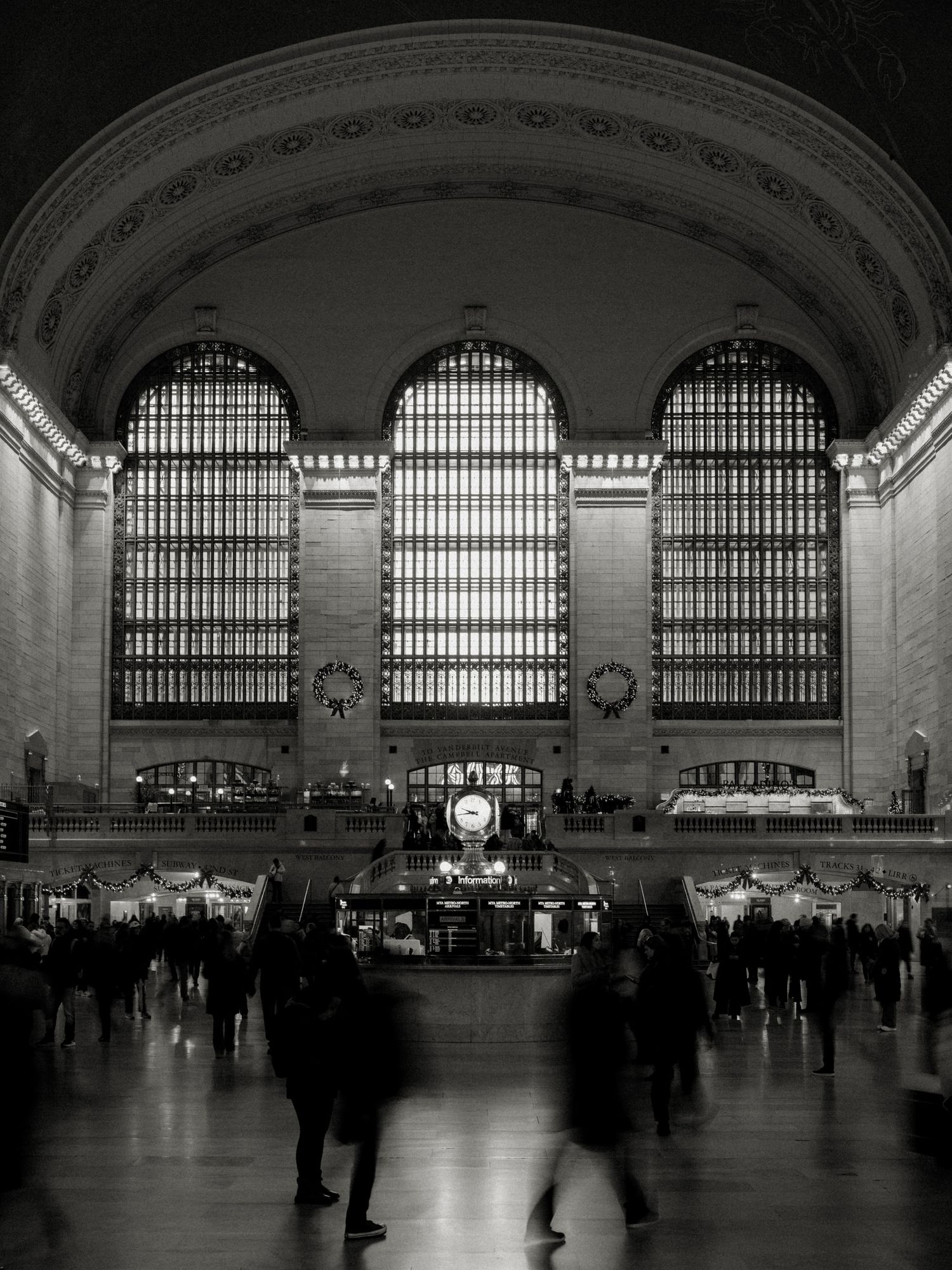 A black and white panoramic sequence showing the grand interior of Grand Central Terminal's main concourse at different exposures.