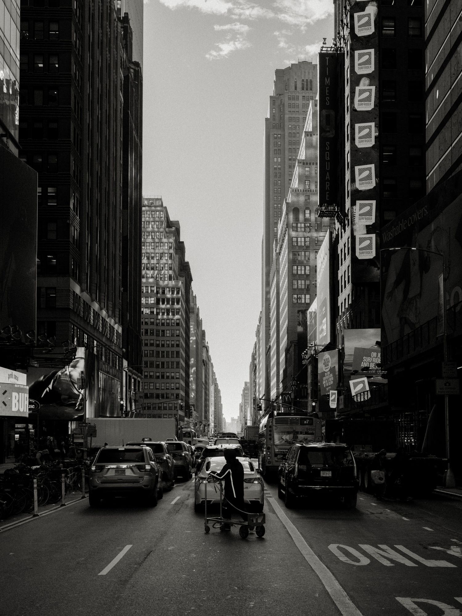 Black and white urban street scene with tall buildings creating dramatic perspective in Manhattan.