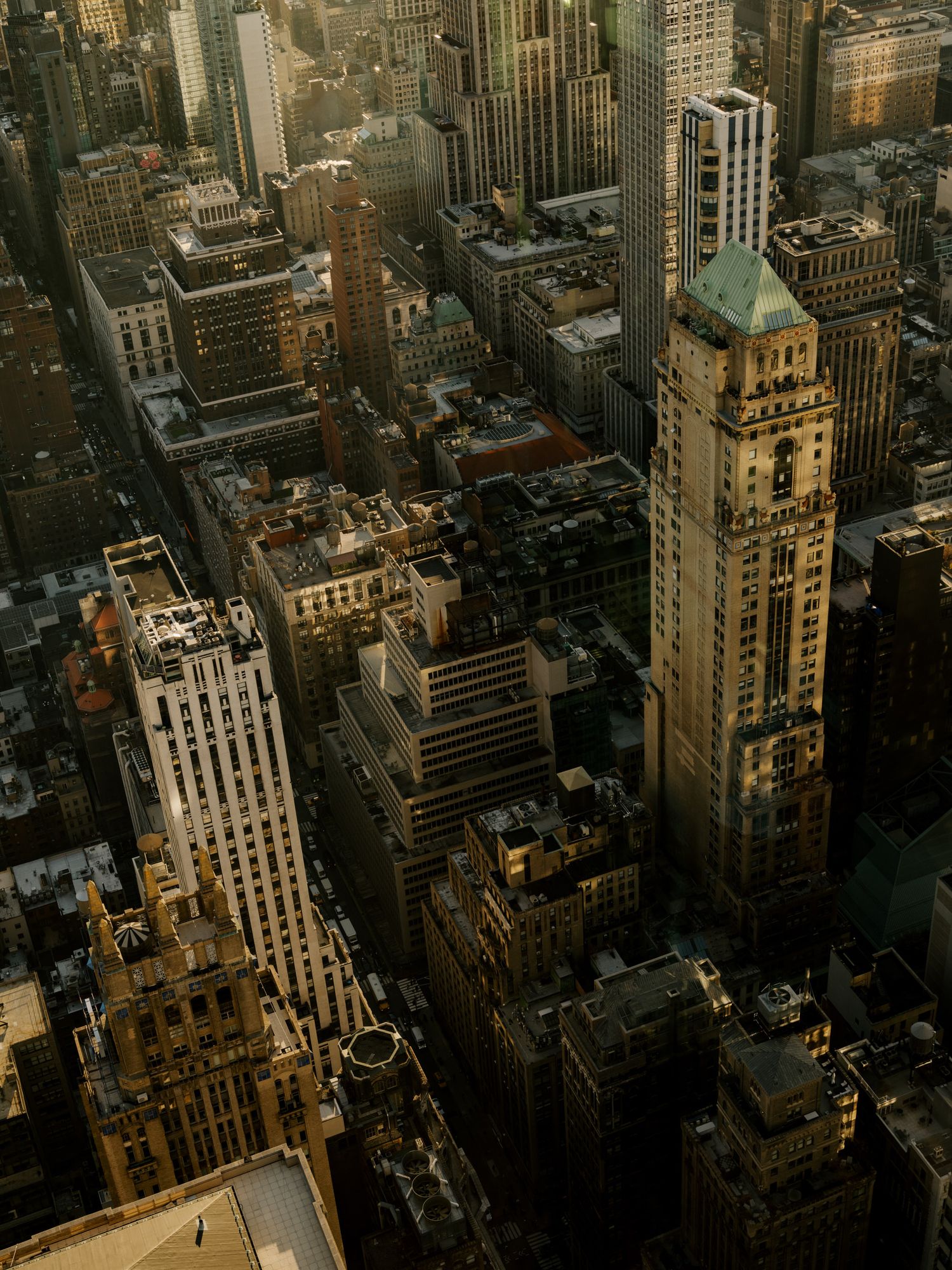 Aerial view of Manhattan's historic architecture and skyscrapers during golden hour with dramatic shadows.