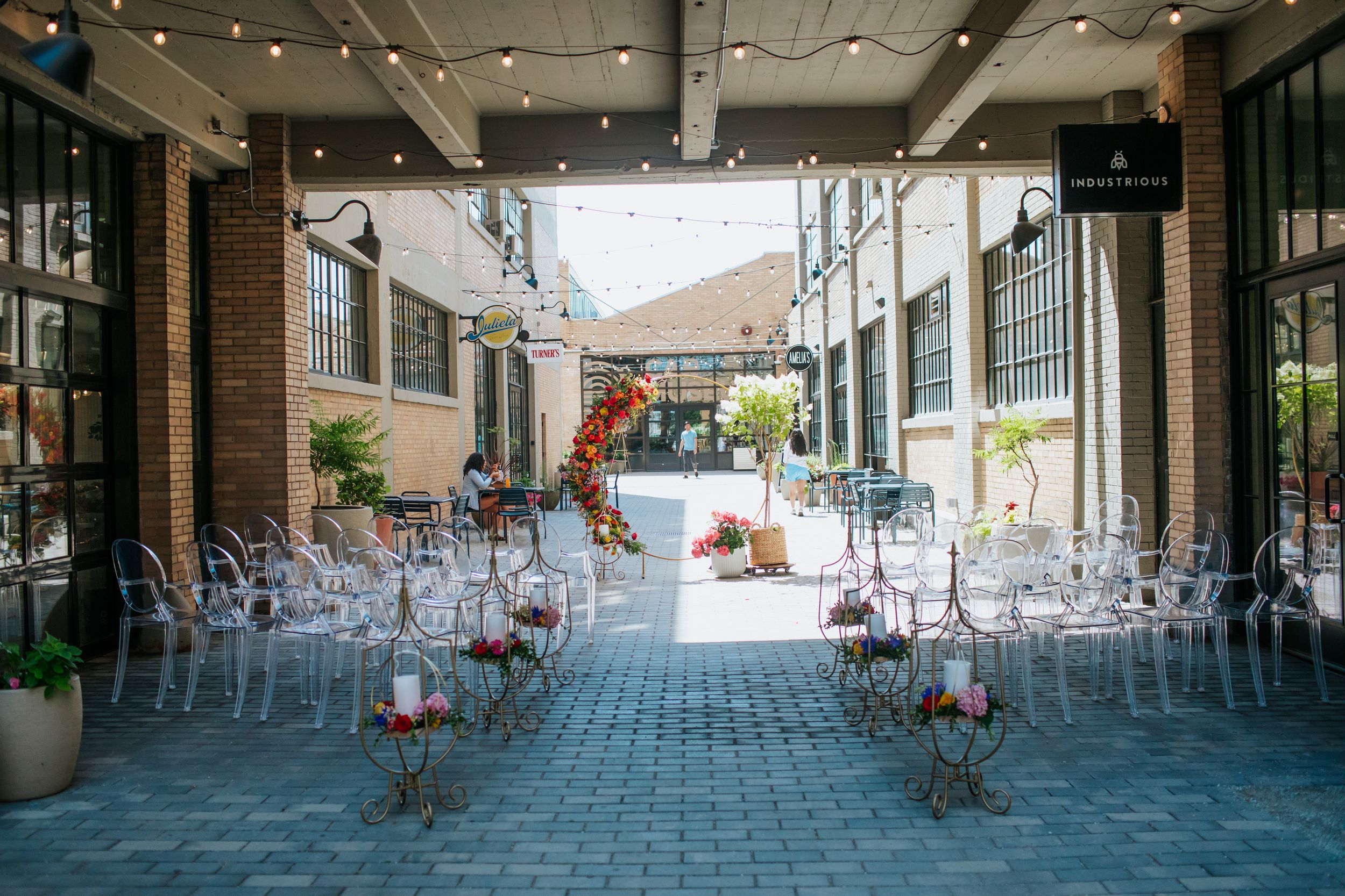String lights illuminate a rustic outdoor patio area with brick walls and wooden beams.