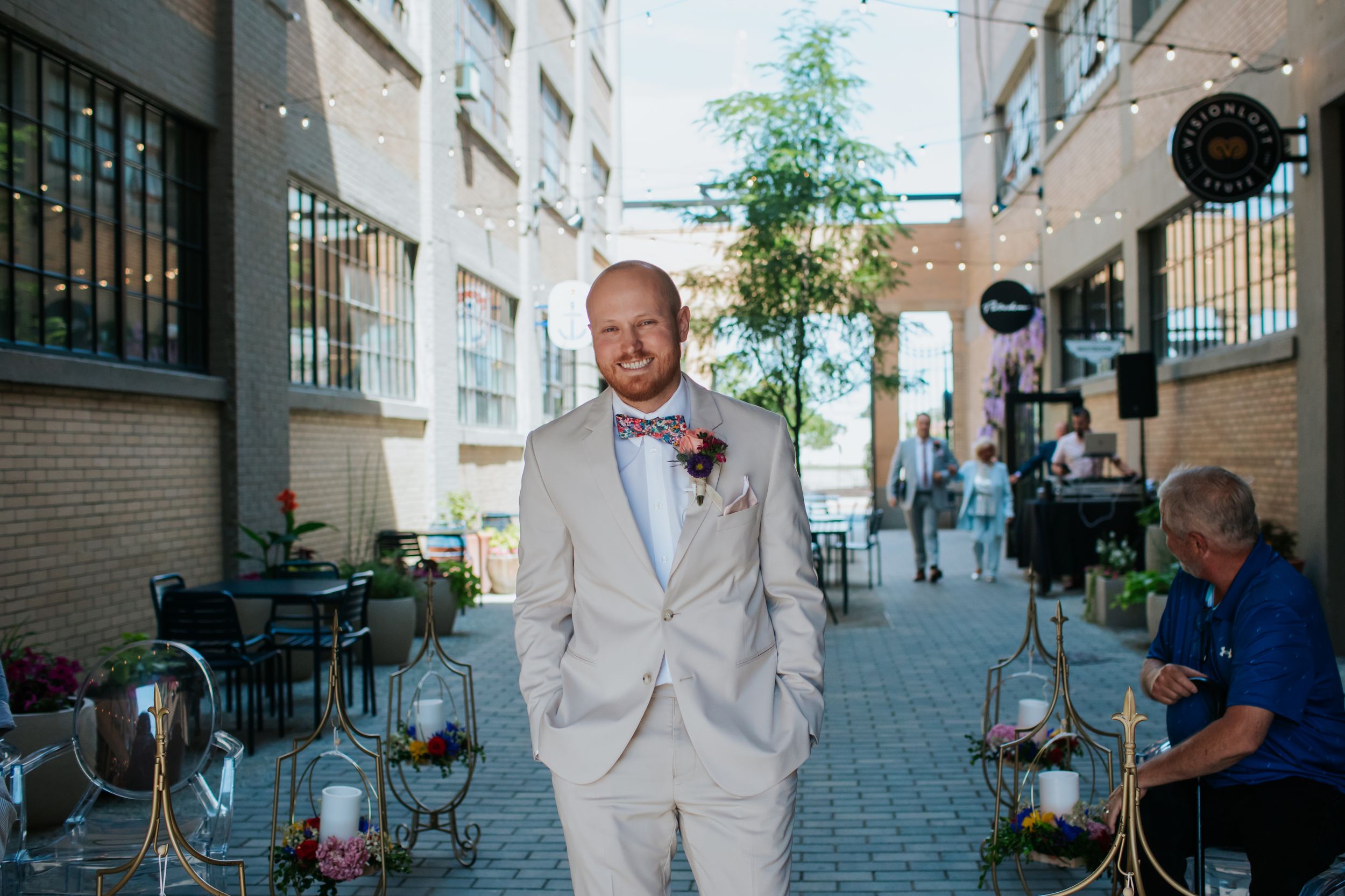 A light beige suit and bowtie ensemble worn at an outdoor urban venue with lantern decorations.