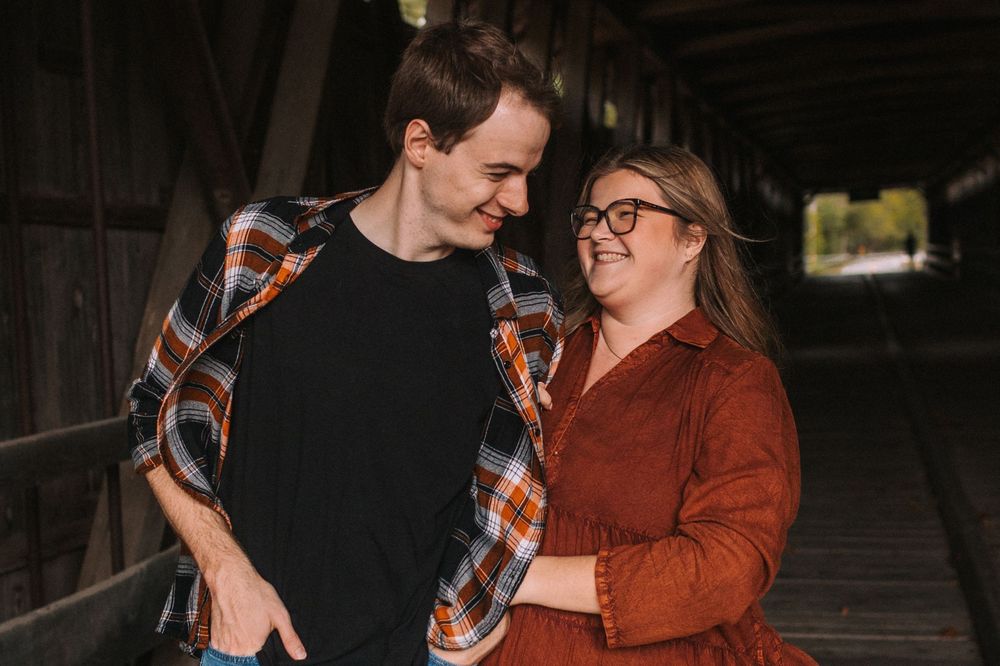 Couple in casual fall attire shares playful moments outdoors.